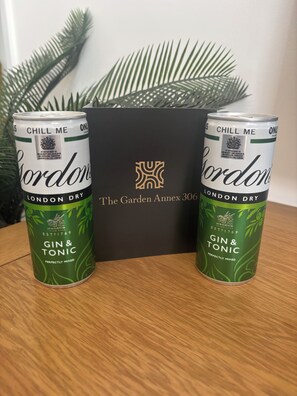 Deux canettes de gin tonic Gordon's London Dry, posées sur une surface en bois, avec en arrière-plan une boîte noire portant l'inscription « The Garden Annex 306 ».