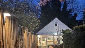 Een huis met een met baksteen bestrate oprit, een houten omheining en een tuin.