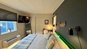 Una habitación de hotel con cama, televisión, escritorio y ventana con persianas.