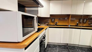 A kitchen with white cabinets, a microwave, a stove, and a sink. - EXPERIENCE PARISIAN ELEGANCE IN THE MOST DESIRABLE DISTRICTS – SAINT GERMAIN (Paris)