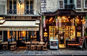 A café named Le Gévaudan with outdoor seating and a display case visible through the window. - EXPERIENCE PARISIAN ELEGANCE IN THE MOST DESIRABLE DISTRICTS – SAINT GERMAIN (Paris)