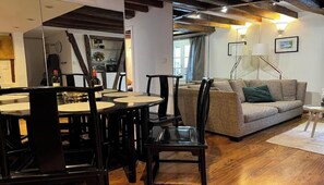 Un salon moderne comprenant un coin repas, un plancher en bois et un canapé agrémenté de coussins.