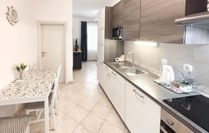 A modern kitchen with a dining area, featuring a microwave, toaster, and sink. - Stunning apartment in Opuzen with WiFi (Opuzen)