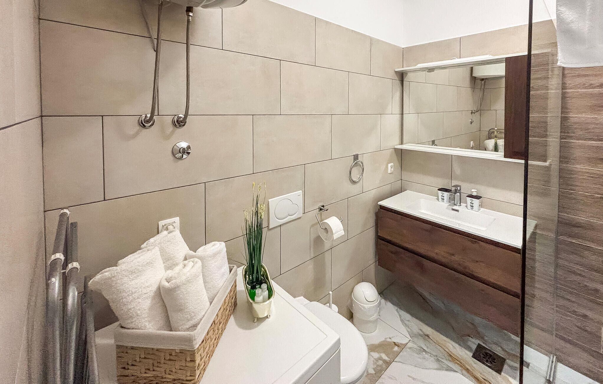 Une salle de bain moderne avec une baignoire, un lavabo et une douche. On trouve des serviettes et des articles de toilette sur le comptoir.
