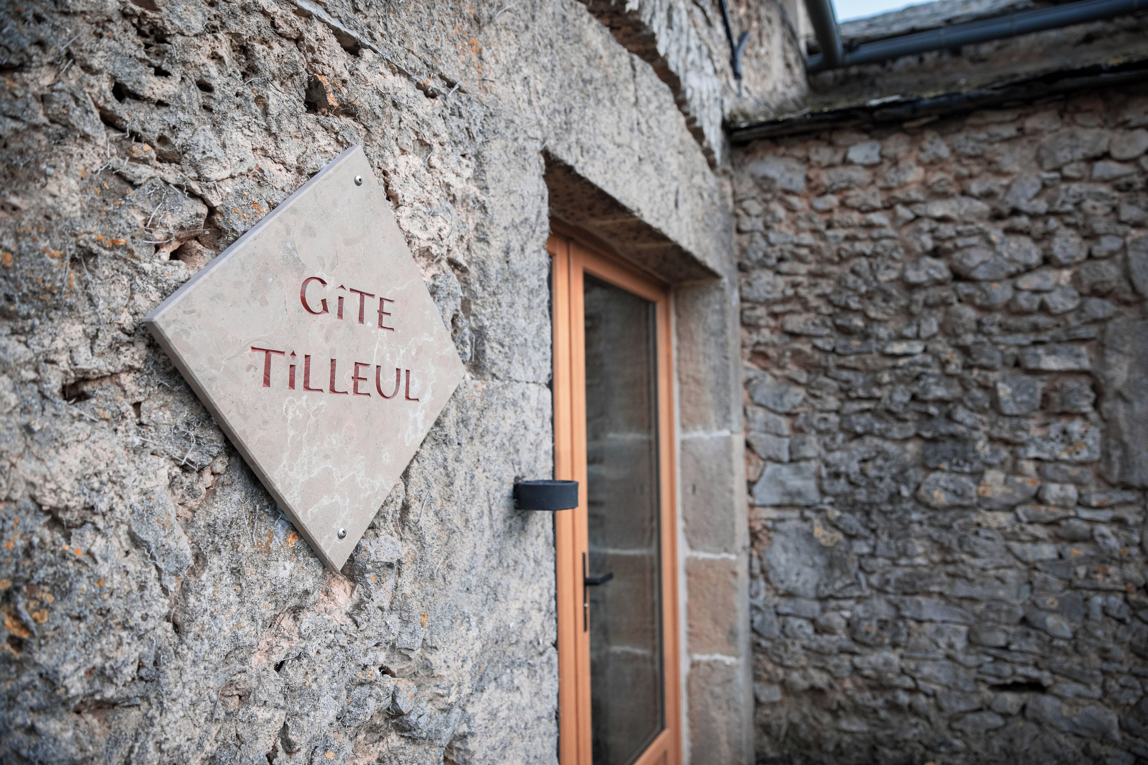 Una pared de piedra con una puerta y un cartel que dice 'GITE TILLEUL'.