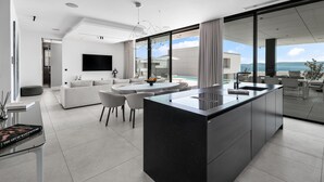 A modern kitchen with a large island, a dining area with a round table, and a living room with a sofa and chairs. - Beautiful home in Ugljan (Ugljan)