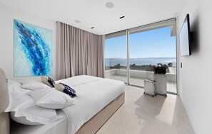 A modern bedroom with a large bed, a painting, a view of the sea, and a luggage cart. - Nice home in Ugljan with private swimming pool, can be inside or outside (Ugljan)