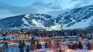 Une ville de montagne enneigée, dotée d’une station de ski, de bâtiments illuminés et d’un télésiège bien visible.