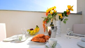 A table set for breakfast with croissants, a fruit bowl, and a vase of flowers. - Amazing apartment in Nin with swimming pool (Nin)