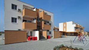 A modern multi-story apartment building with balconies, a covered outdoor area, and a playground. - 2 bedroom pet friendly apartment in Nin (Nin)