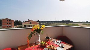 A balcony with a table set for a meal, a vase with flowers, and a bottle of wine. - 2 bedroom pet friendly apartment in Nin (Nin)