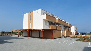 Un immeuble moderne à plusieurs étages, doté d’un toit plat, d’un espace extérieur couvert et d’un parking.
