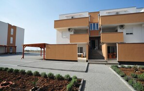 Un bâtiment moderne à plusieurs étages, doté d’un escalier central, d’un espace extérieur aménagé pour s’asseoir et d’un jardin paysager.