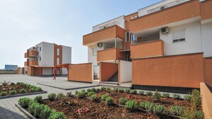 Ein modernes Mehrfamilienhaus mit Balkonen, einer überdachten Außenbereich und einem angelegten Garten.