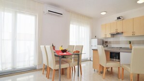 A modern kitchen with wooden cabinets, a dining table with chairs, and a large window with sheer curtains. - Amazing apartment in Nin with swimming pool (Nin)