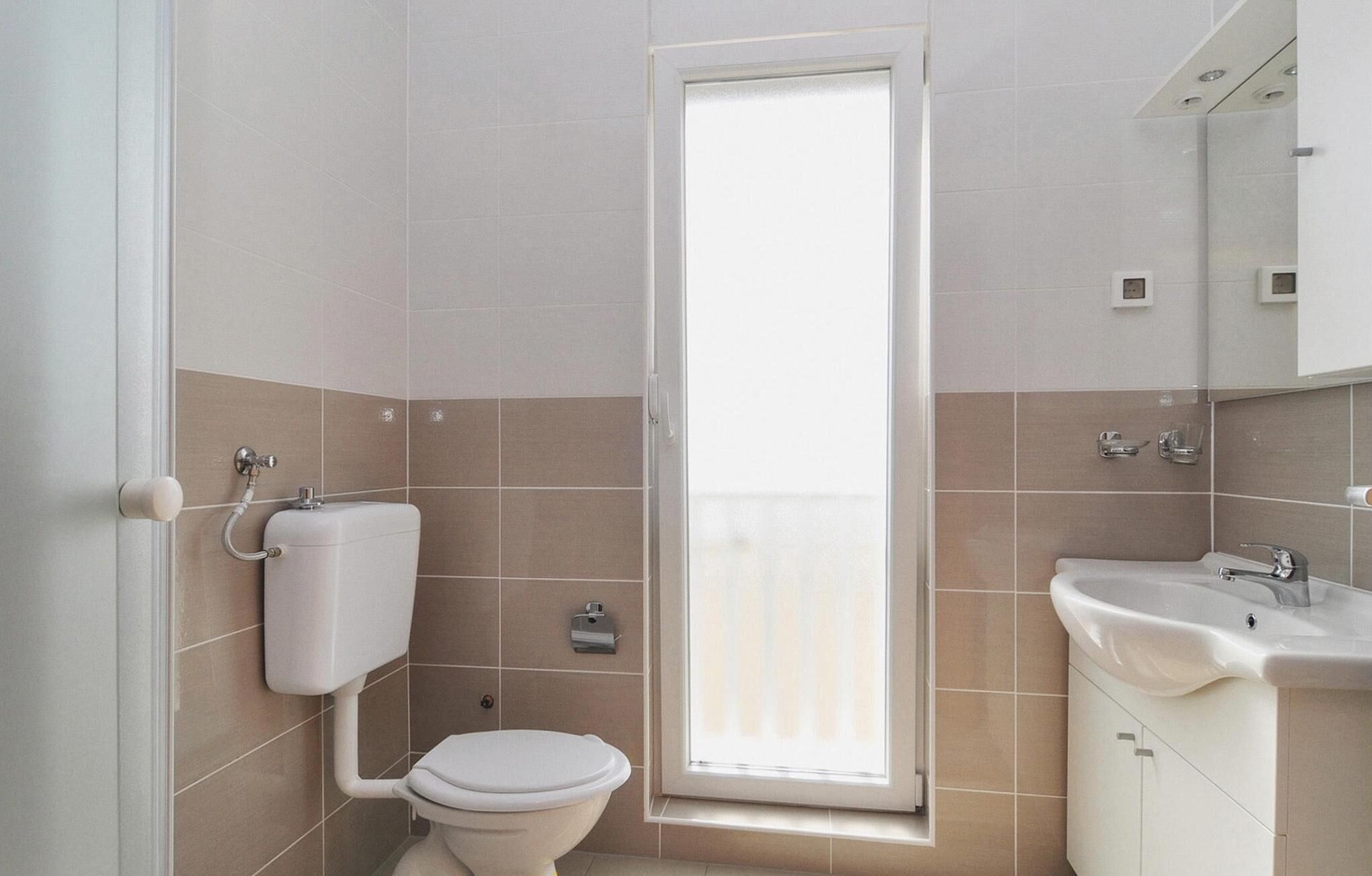 A bathroom with a toilet, a sink, and a window.