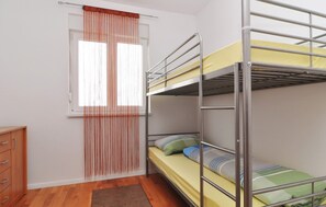 Ein Schlafsaalzimmer mit Etagenbetten, einem Holzschrank und einem Fenster mit Vorhängen.