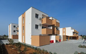 A modern multi-story residential building with balconies, a covered outdoor seating area, and a landscaped courtyard. - 2 bedroom beautiful apartment in Nin (Nin)