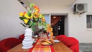 Ein Esstisch mit weißer Blumenvase, Tellern, Gläsern und einer karierten Tischdecke.