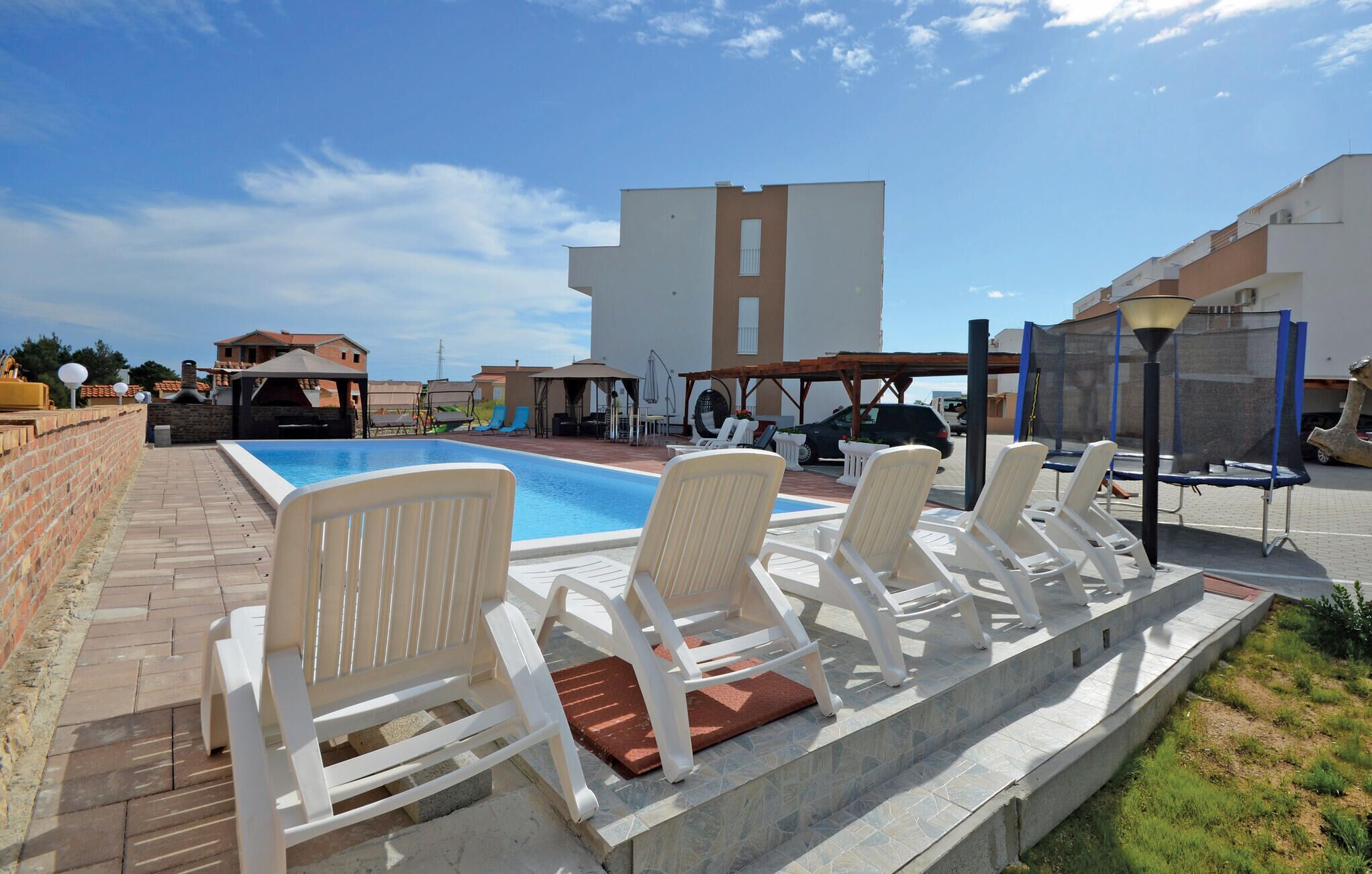 A pool area with white lounge chairs and a clear blue sky.