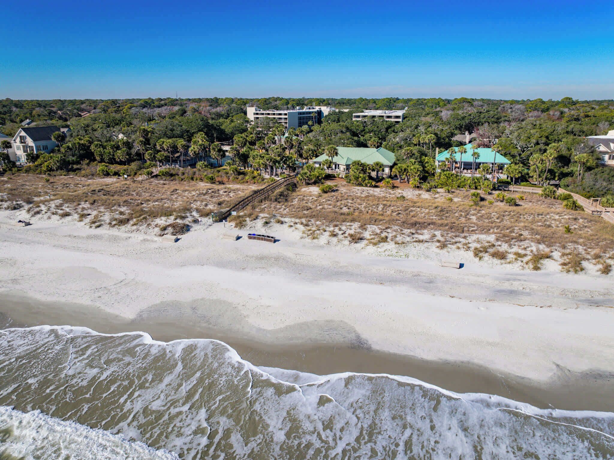 A coastal area with a sandy beach, a bridge, and buildings with green roofs.