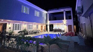 Un bâtiment à deux étages doté d’une piscine, d’un espace extérieur aménagé et d’un bar.