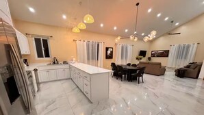 Une cuisine moderne avec des meubles blancs, un îlot central et des luminaires suspendus.