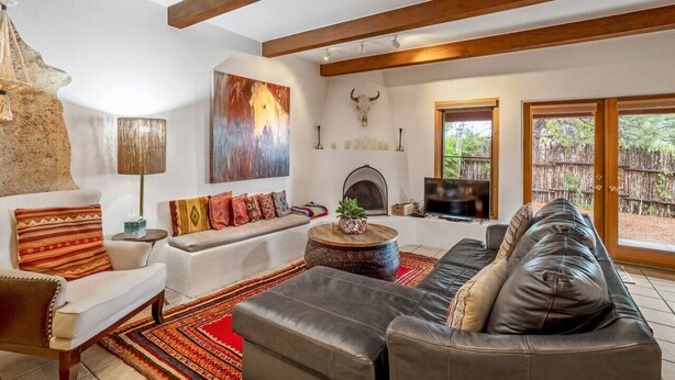 A cozy living room with a fireplace, a sofa, a coffee table, and a television. - Cielo Grande · Near Santa Fe Plaza, Small Fenced Yard, Parking (Santa Fe)