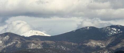 A mountainous landscape with snow-capped peaks and a cloudy sky.