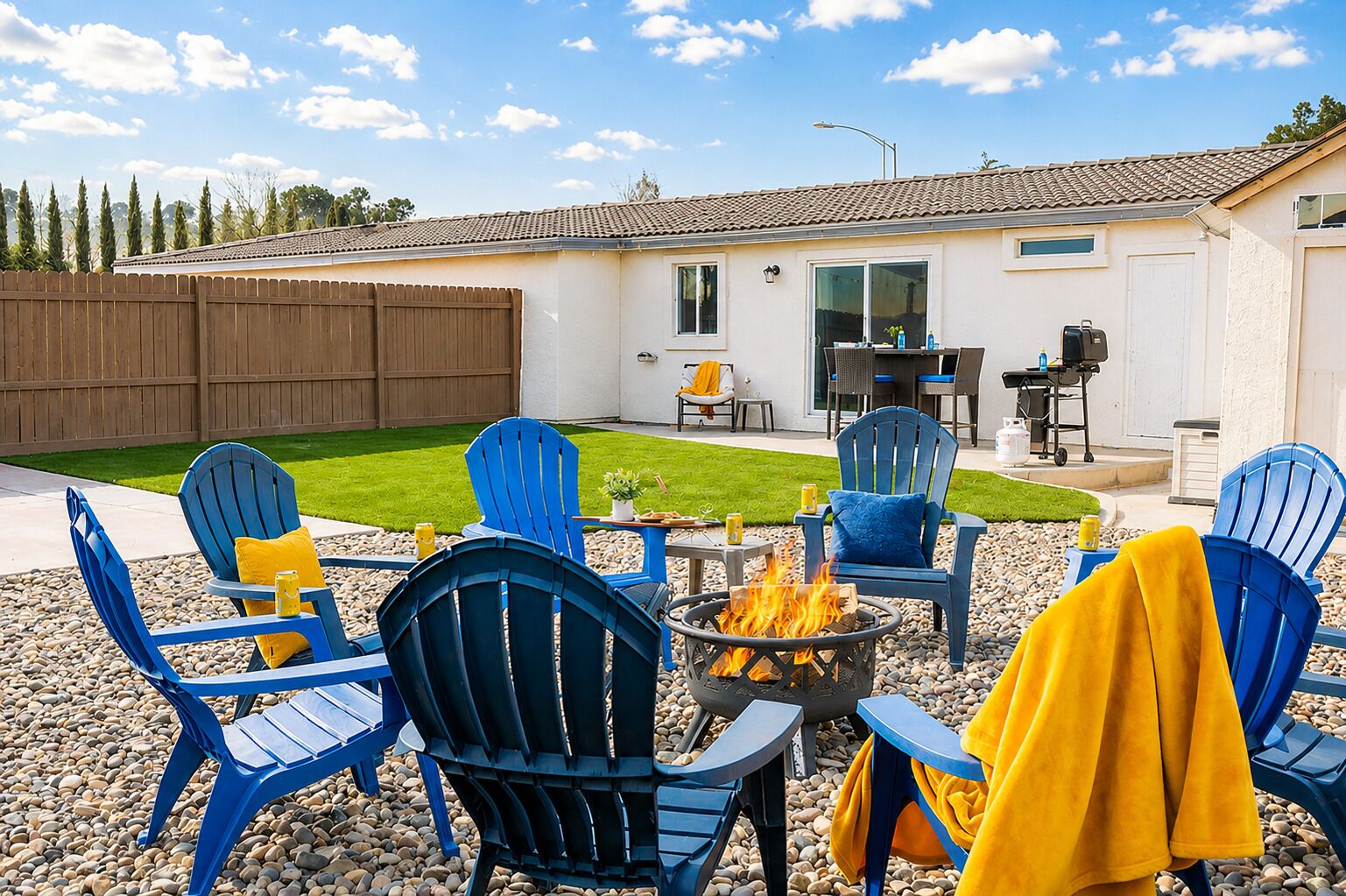 Un jardin avec un espace aménagé pour s’asseoir à l’extérieur, un foyer et une maison dotée d’un patio.