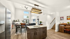 A spacious kitchen with a central island, wooden cabinets, and a modern chandelier.