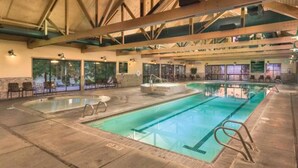 An indoor swimming pool with a clear view of the pool area, including the pool's edge, steps, and a lifeguard chair.