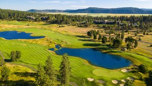 A golf course with multiple ponds, trees, and distant mountains.