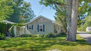 A single-story house with a front yard, a large tree, and a gravel driveway.