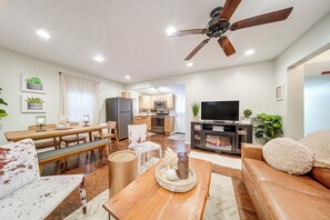 Una sala de estar moderna con una mesa de comedor de madera, un sofá, un televisor y un ventilador de techo.