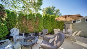 An outdoor patio with a fire pit, chairs, and a table.