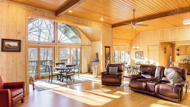 Un salon spacieux doté de parquets en bois, d’un canapé en cuir et d’un coin repas avec une table et des chaises.