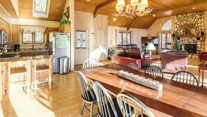 Une cuisine spacieuse avec des meubles en bois, un coin repas doté d’une grande table en bois et une cheminée en pierre.