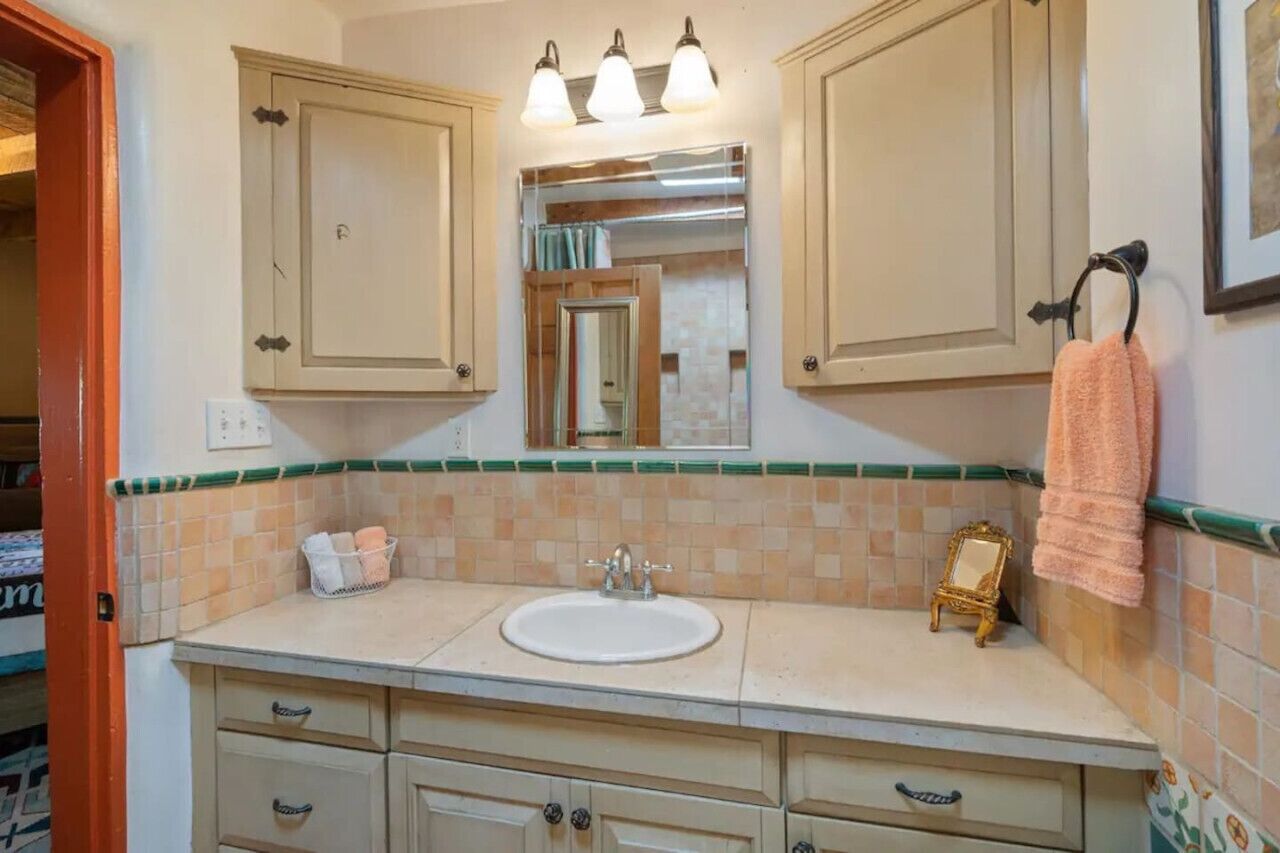A bathroom with a sink, mirror, and cabinets.