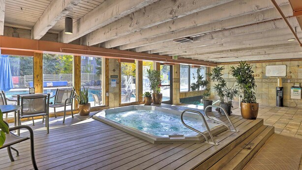 A wooden deck with a hot tub, chairs, and potted plants. - Continental Divide Views: Lakefront Keystone Condo (Keystone)