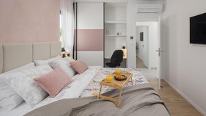 A modern bedroom with a large bed, a bedside table with a tray of breakfast, a desk with a chair, and a TV mounted on the wall. - Gorgeous home in Sveti Petar u Sumi (Sveti Petar u Sumi)
