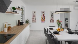 A modern kitchen with a wooden countertop, built-in appliances, and a dining area with a white table set for four. - Gorgeous home in Sveti Petar u Sumi (Sveti Petar u Sumi)