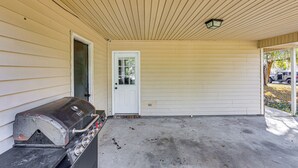 A covered porch with a grill, a white door, and a vehicle parked outside. - 12 Mi to Dtwn Savannah: Remodeled Family Getaway! (Pooler)