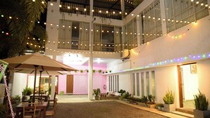 Un patio con mesas al aire libre, luces colgantes y plantas en macetas.