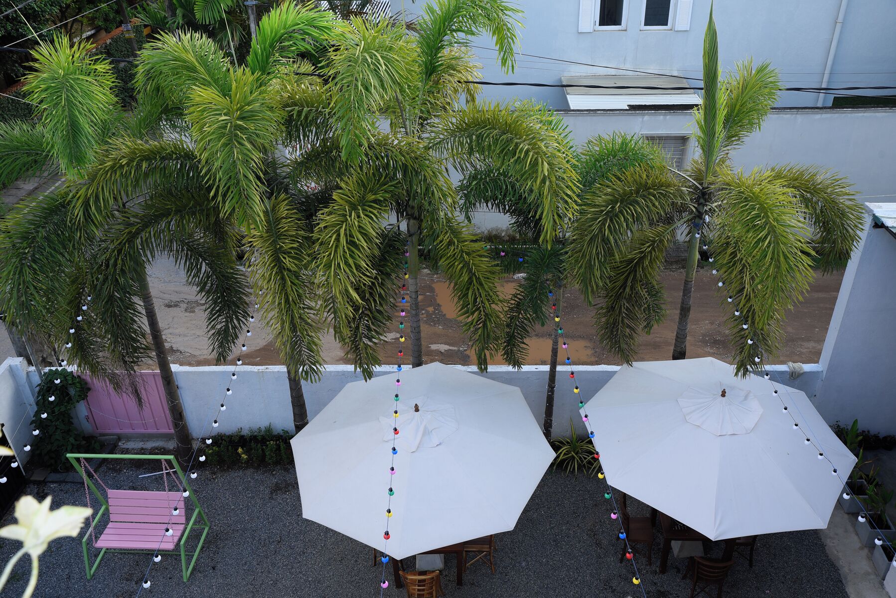 Une terrasse sur le toit, agrémentée de deux parasols blancs, entourée de palmiers et recouverte de gravier.