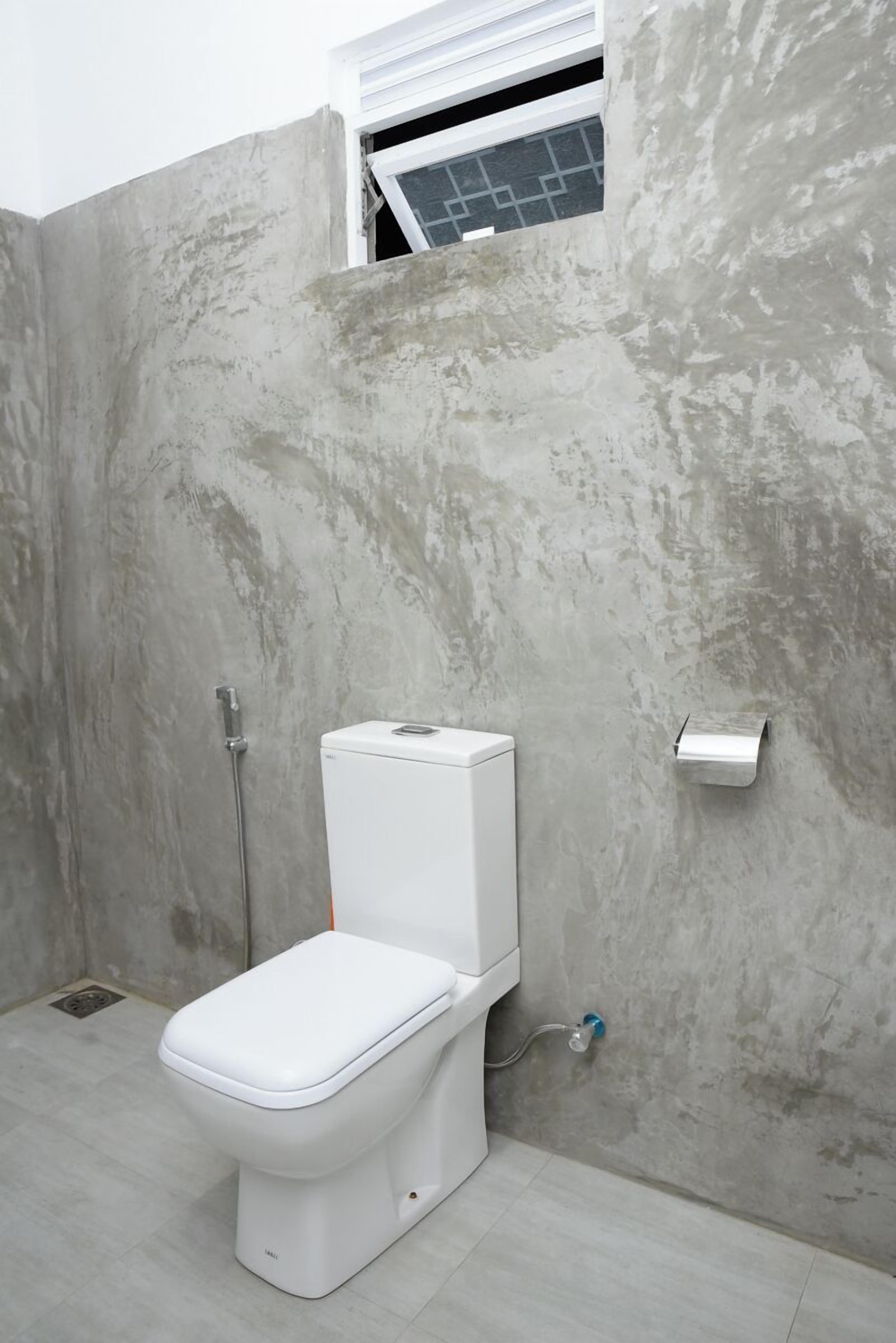 Un baño moderno con inodoro blanco, ducha y dispensador de toallas.