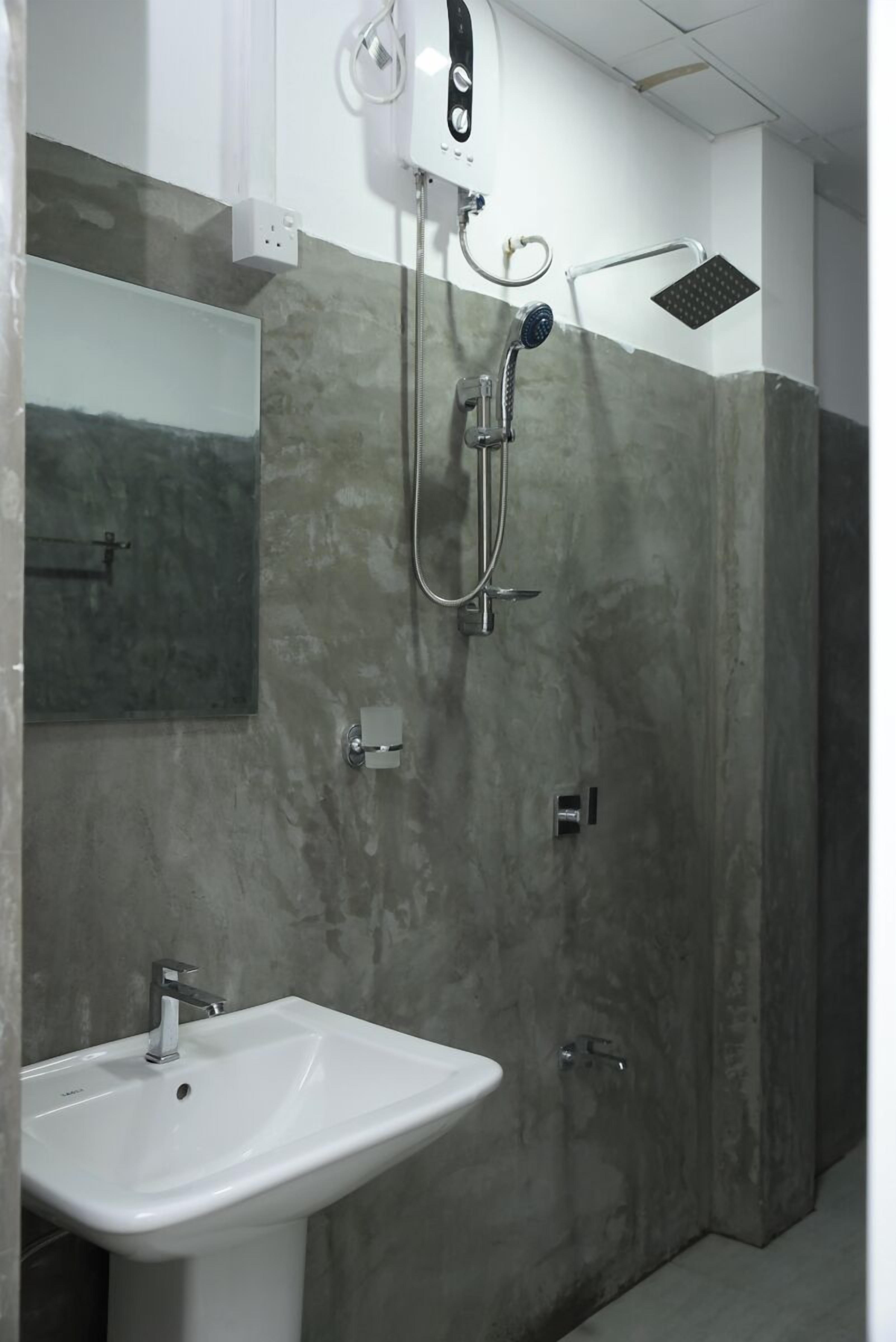 A bathroom with a white sink, a handheld showerhead, and a wall-mounted showerhead.