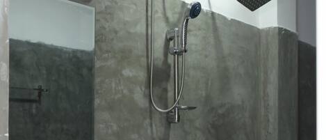 Ein Badezimmer mit einem weißen Waschbecken, einer Duschbrause und einer fest installierten Duschbrause.