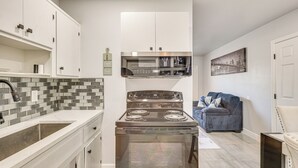 A modern kitchen with white cabinets, a stainless steel stove, and a tiled backsplash. - Walk to Shops, Dining & Casino: Dania Beach Home (Dania Beach)