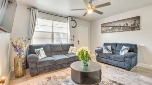A living room with two sofas, a coffee table, a clock, and a ceiling fan. - Walk to Shops, Dining & Casino: Dania Beach Home (Dania Beach)